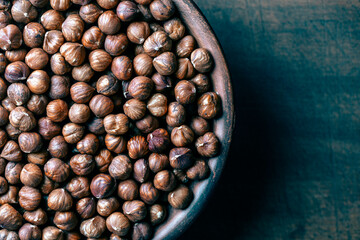 Dry hazelnuts in a ceramic plate on a wooden background. Heap of peeled hazelnuts kernels, top view, copy space for text