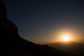 The moon rises from behind the distant hills in Uzbekistan's Boysuntov Range.; Uzbekistan.