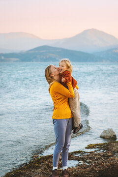 Mother kissing hugging daughter walking outdoor family lifestyle travel together summer vacations woman with child at the lake Mothers day holiday