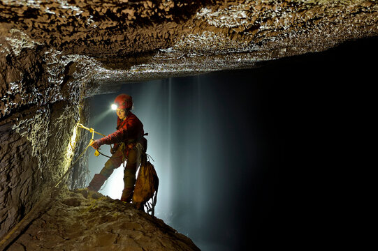 A cave explorer prepares to descend down into the black chasm below her in the Queen of the Nile section of San Wang Dong.