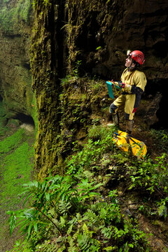 A speleologist on a small ledge overlooking the vast floor surface of Niubizi Tian Keng in the Er Wang Dong cave system.