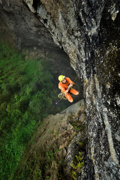 A cave explorer climbs a thin rope up to a small ledge overlooking the vast floor surface of Niubizi Tian Keng in the Er Wang Dong cave system.