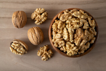 Peeled walnuts and whole walnuts in wooden bowl
