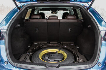 Spare wheel in the trunk of a modern car. Jack lifting and a spare tire in rear of car.