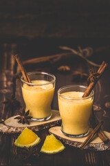 Two glasses of eggnogg with cinnamon sticks on dark wooden background. Auld Man's milk, Coquito or Creme de Vie or Eierlikör.