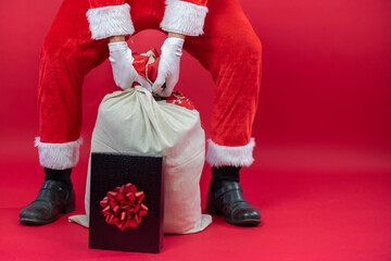 Nahaufnahme von einem Weihnachtsmann, der ein Sack voller Geschenke hält, auf roten Hintergrund....