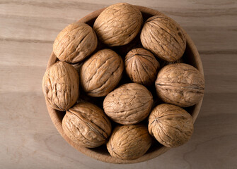 Bunch of whole walnuts in shell in wooden bowl