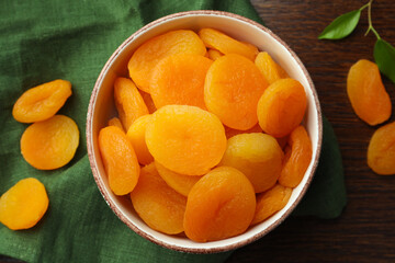 Bowl of tasty apricots on wooden table, flat lay. Dried fruits