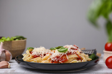Delicious pasta with tomato sauce, basil and parmesan cheese on white wooden table
