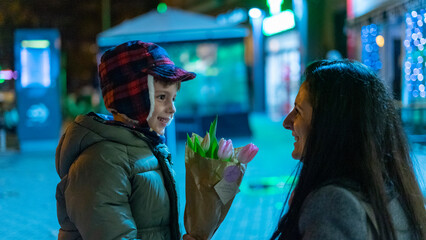 niño regalando flores a mujer