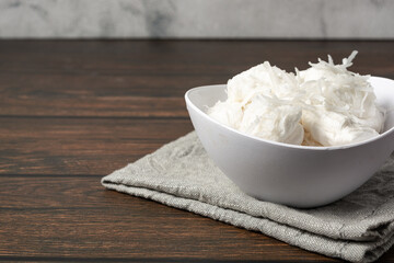 bala de coco or brazilian coconut candy, a gourmet homemade sweet dessert made of coconut on a white bowl.