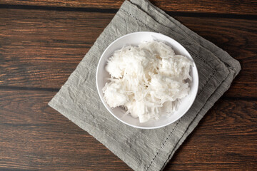 bala de coco or brazilian coconut candy, a gourmet homemade sweet dessert made of coconut on a white bowl. top view flat lay