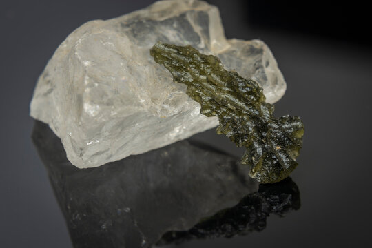 Moldavit stone and white big stone on shiny black table