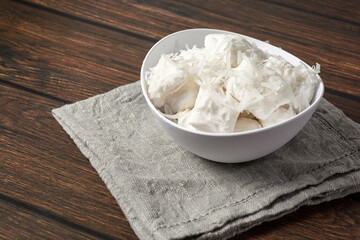 bala de coco or brazilian coconut candy, a gourmet homemade sweet dessert made of coconut on a white bowl
