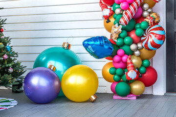 A white siding building exterior with balloons and large ornamentsfor a festive Christmas decoration or decor