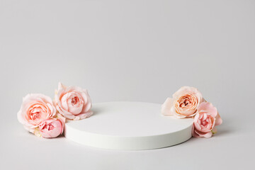 Empty wide white podium and pink roses on light grey background. Minimal cosmetic template. Round...