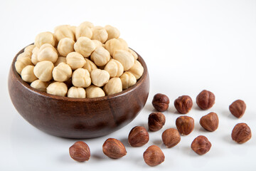 View of a bowl full of hazelnuts on white background
