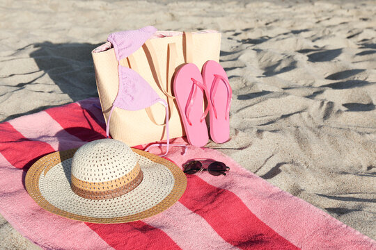 Towel with bag and beach accessories on sand