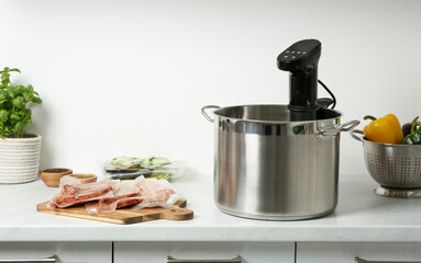 Thermal immersion circulator in pot and vacuum packed food products on countertop in kitchen. Sous...