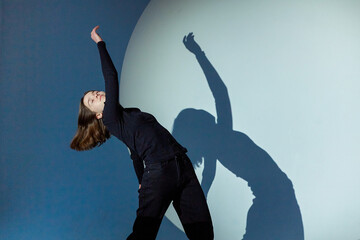 Teenage girl dances in a spotlight.