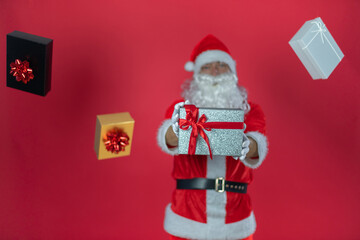 Portrait von einem verkleideten Weihnachtsmann mit Geschenk, isoliert auf roten Hintergrund im Studio im Querformat