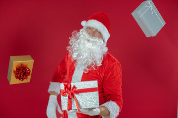 Portrait von einem verkleideten Weihnachtsmann mit Geschenk, isoliert auf roten Hintergrund im...