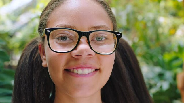 Face, girl and student in nature, garden and park to study wildlife, ecosystem and environment for school, education or zoo. Portrait, smile and happy teenager with glasses, nerd and geek in Colombia