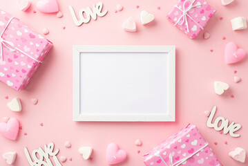 Valentine's Day concept. Top view photo of photo frame present boxes heart shaped marshmallow candles inscriptions love and sprinkles on isolated pastel pink background with copyspace