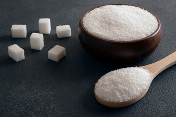 Cube sugar and granulated sugar on dark background,closeup
