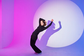 Teenage girl dances in a spotlight.