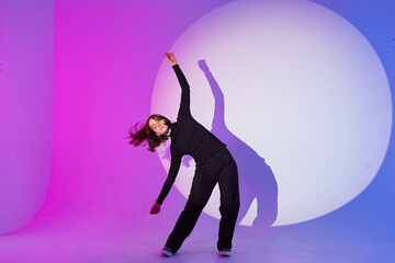Teenage girl dances in a spotlight.