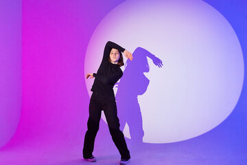 Teenage girl dances in a spotlight.