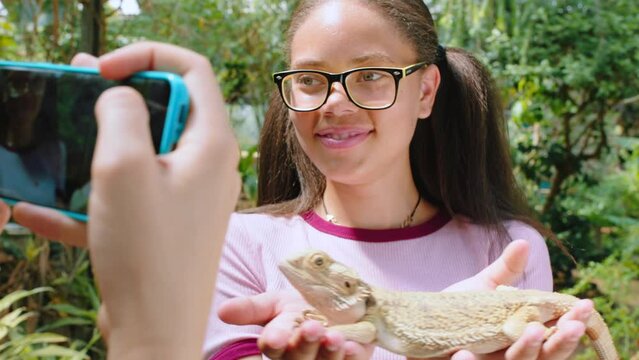 Iguana, friends and phone with girl in zoo for selfie, environment and social media. Ecosystem, nature and learning with teenagers and lizard in sanctuary for wildlife, digital and mobile together