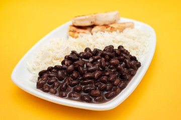 Healthy food with chicken breast, beans and rice on a white plate.