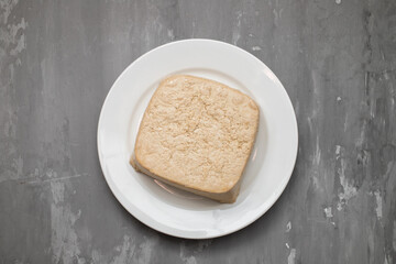 raw tofu block on white small dish on ceramic