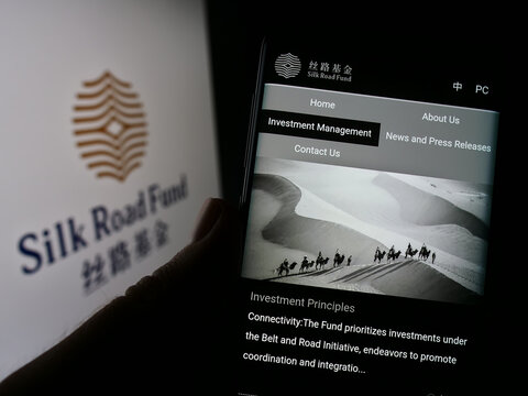 Stuttgart, Germany - 12-04-2022: Person holding cellphone with web page of Chinese investment fund Silk Road Fund on screen in front of logo. Focus on center of phone display.