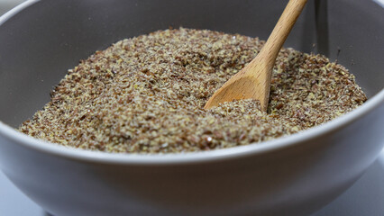 Cuchara de madera cogiendo semillas de lino de un cuenco
