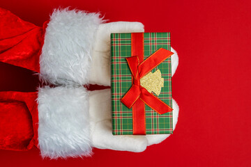Santa's hands are holding a gift for Christmas. red background 