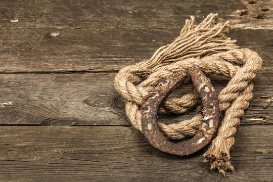 Horseshoe and vintage rope. Concept of good luck for St. Patrick's Day. Old wooden boards background