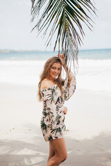Beautiful girl near the palm tree on the tropical beach