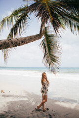 Beautiful girl near the palm tree on the tropical beach
