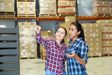 Portrait of confident hispanic females storage workers talking at workplace