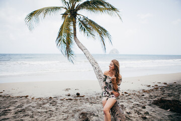 Fototapeta na wymiar Beautiful girl near the palm tree on the tropical beach