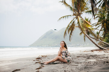 Fototapeta na wymiar Beautiful girl near the palm tree on the tropical beach