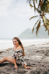 Beautiful girl near the palm tree on the tropical beach