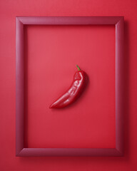 Pepper in wooden picture frame on red background