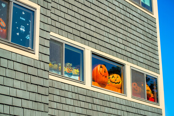 Decorative halloween window with bright multicolored orange pumpkins and gray wooden exterior on...
