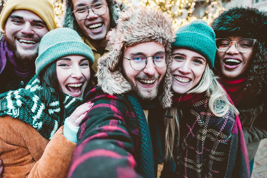 International group of friends taking selfie  wearing warm fashion clothes - Happy life style concept with millenial people having fun together outside on winter holidays- friendship concept