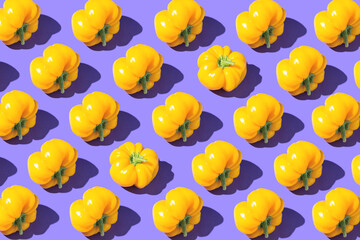 Bright creative pattern made of yellow bell pepper on violet background. Minimal style. Healthy food ingredient concept