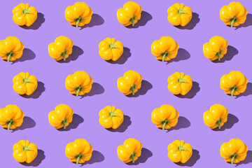 Bright creative pattern made of yellow bell pepper on violet background. Minimal style. Healthy food ingredient concept